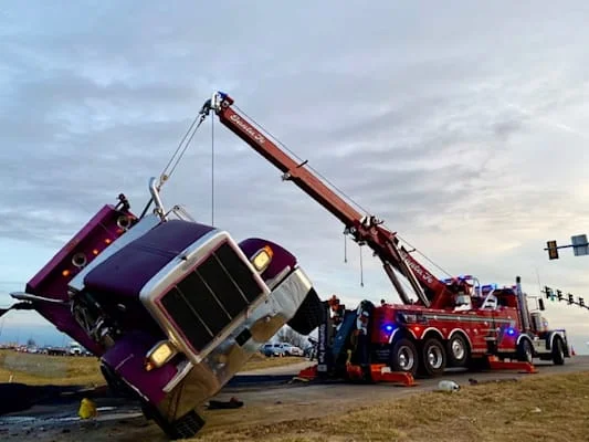 Heavy-duty tow truck winching bulldozer out of mud at construction site